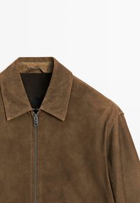 Brun ruskindsjakke med krave, der har en frontlynlås og en glat overflade. Designet er enkelt og struktureret.