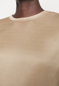 Beige Hemd mit kurzen Ärmeln aus glattem Stoff, mit rundem Ausschnitt und minimalistischem Design ohne sichtbare Muster oder Hardware-Details.