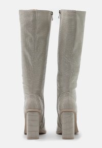 Bottes grises à motif crocodile, montant jusqu'au genou, avec une pointe ronde et un talon épais. Fermeture éclair latérale et texture lisse.