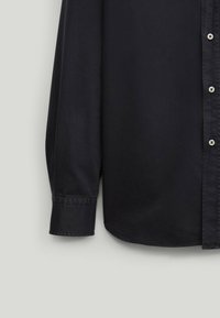 Camicia a maniche lunghe di un blu scuro realizzata in tessuto morbido, con colletto button-down, imbottitura con bottoni e dettagli ai polsini.