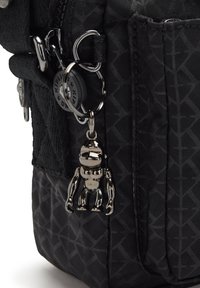 Black fabric backpack with geometric pattern, featuring a shiny silver keychain of a monkey figure and multiple zippered compartments.