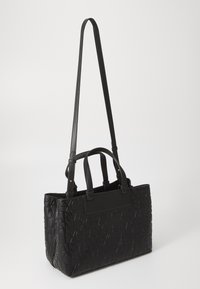 Svart syntetisk totebag med preget tekst, doble topphåndtak, og et langt justerbart stropp. Jevn tekstur og rektangulær form.