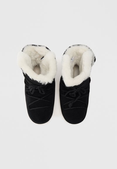 Bottines noires en suède à enfiler avec une doublure en fausse fourrure blanche, présentant un bout arrondi, des lacets décoratifs et un dessus texturé.