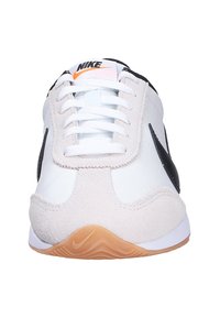 Zapatilla Nike con una parte superior de cuero blanco y acentos de ante gris claro, detalles en negro y una suela de goma de color goma. Diseño de cordones.