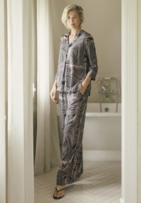 Set de pyjama drapé en marine avec des motifs blancs tourbillonnants. Haut à manches longues avec une coupe décontractée, pantalon ample et décolleté ouvert. Tissu léger.