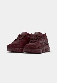 Bordeauxkleurige New Balance sneakers met een Textuurstof bovenzijde, een ronde neus, dikke zool en opvallende branding aan de zijkant en tong.
