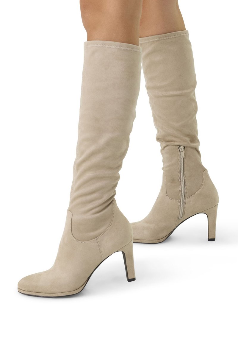 Beige kniehoge laarzen van zacht suède. Voorzien van een elegant design, een spitse neus en een rits aan de zijkant. De stiletto hak zorgt voor extra hoogte.