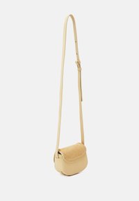 Piccola borsa a tracolla giallo chiaro con corpo in pelle liscia e patta in camoscio. Presenta una tracolla regolabile e una base arrotondata.