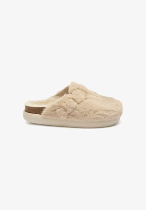 Pantofole in beige morbido con una texture pelosa, caratterizzate da una suola leggera crema e un delicato accento marrone lungo il bordo.