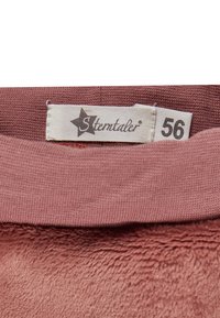 In einen pinken Stoff eingenähtes Etikett mit der Marke "Stemtaler" und einem Größenetikett mit der Bezeichnung "56".