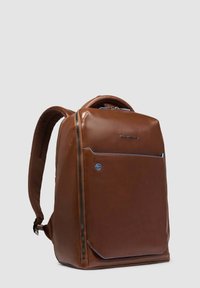 Mochila de cuero marrón con un diseño elegante, que cuenta con un bolsillo frontal con cremallera y detalles en azul. Tirantes ajustables y un panel trasero texturizado.