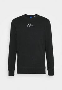 Sudadera negra de algodón, con mangas largas, escote redondo y un logo bordado en blanco en el pecho. Textura suave.