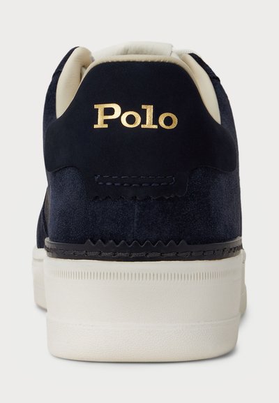 Jūras spēku zilo zamšādu sporta apavu ar baltu gumijas zoli. Iezīmējas ar zeltītu "Polo" logo uz papēža, gludu tekstūru un detalizētu šuvju apstrādi malās.