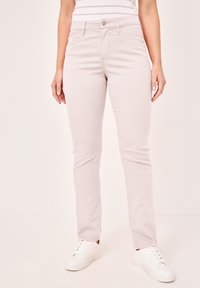 Helle rosa Slim-Fit-Jeans aus Baumwollmischung, mit frontalen Taschen, Gürtelschlaufen und Reißverschluss mit Knopfverschluss. Kombiniert mit weißen Sneakers.