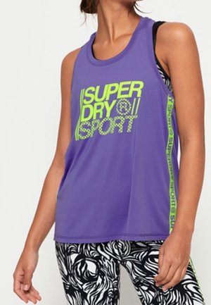 Paarse mouwloze sporttanktop met de tekst "SUPERDRY SPORT" in neon groen en zijaccenten. Gemaakt in combinatie met zwart-witte leggings met patroon.