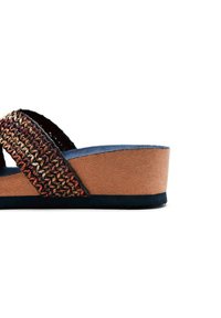 Sandale plateforme marron avec une sangle tressée dans des tons rouges et dorés. Elle présente une tige en simili-suède texturé et une semelle intérieure rembourrée.