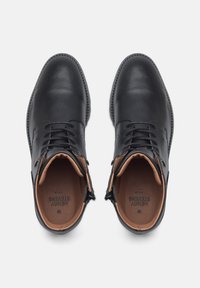 Stivali alla caviglia in pelle nera con una texture liscia, punta rotonda e interno di colore beige in contrasto. Presentano un design con lacci e un sottile dettaglio di cucitura.