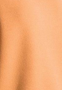 Tejido suave y acanalado en un cálido color durazno, con una textura lisa y un brillo sutil, adecuado para prendas de vestir o accesorios.