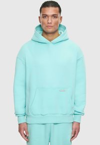 Türkiser oversized Hoodie aus weichem Material mit einer Tasche auf der Vorderseite, gerippten Bündchen und einer Kapuze mit Kordelzug sowie einem kleinen Logotag.