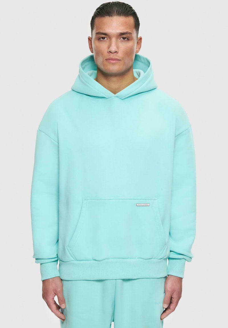 Türkiser oversized Hoodie aus weichem Material mit einer Tasche auf der Vorderseite, gerippten Bündchen und einer Kapuze mit Kordelzug sowie einem kleinen Logotag.