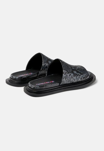 Zwarte slide-sandalen met een gestructureerd slangenhuidpatroon, open teen en platte zool. Heeft een gladde zwarte binnenkant met een logoafdruk.