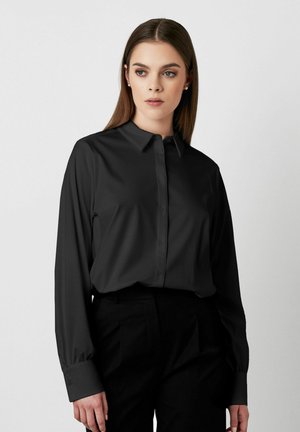 Langärmliges schwarzes Hemd mit einem maßgeschneiderten Kragen, einer Knopfleiste vorne, glatter Textur und strukturierten Manschetten, kombiniert mit schwarzen Hosen.