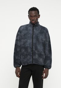 Fleecejacke in Dunkelgrau mit hohem Kragen, durchgehendem Reißverschluss und elastischen Bündchen. Verfügt über eine weiche, strukturierten Oberfläche und eine lockere Passform.