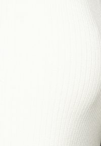 Žebrovaná bílá pletenina se hladkým povrchem, která má vertikální pruhy a mírný lesk, vhodná pro přiléhavé oděvy.