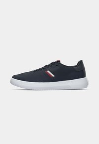 Marineblå sneakers med en tekstureret overdel, hvid gummisål og rød/hvid stribet detalje. Har sorte snørebånd og et lavprofil design.