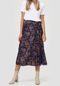 Marinblå blommig midikjol med en plisserad design, prydd med bronzefärgade blommor. Elastiska midjeband, kombinerad med en vit t-shirt och ankelskor.