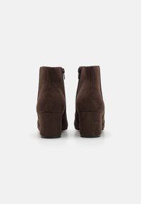 Brown suede ankle boots with a slightly rounded toe, a chunky heel, and a side zipper for closure. Smooth texture with minimal accents.