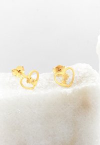 Guld hjärtformade stiftörhängen med utskurna blommor, med en slät yta och standard fjäderbackar.