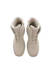 Un paio di stivali invernali beige U.S. Polo Assn. con fodera in pelliccia, lacci e cerniere laterali, visti dall'alto su uno sfondo bianco.