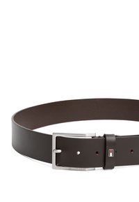 Ceinture en cuir brun avec une texture lisse, boucle en métal argenté rectangulaire et une petite étiquette de logo. Présente plusieurs trous d'ajustement.