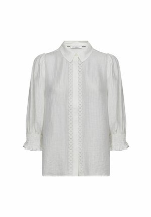 Balta teksturēta blūze ar spārniem piedurknēs, mazu apkakli, pogu rāvējslāni ar apļveida mežģīņu apdari un cieši savērptiem volānu aprocēm.