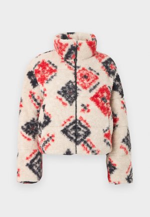 Σέρπα ζακέτα με φερμουάρ και ψηλό γιακά, με κρέμ βάση και διαμάντι σχέδιο σε κόκκινο και μαύρο. Μαλακή υφή και φουσκωτή σιλουέτα.