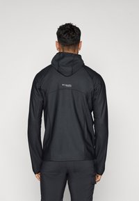 Fekete kabát kapucnival, textúrált anyagból, testhezálló fazonnal. Jellemzője a logo a hátsó felső részen, hosszú ujjakkal és formázott sziluettel.