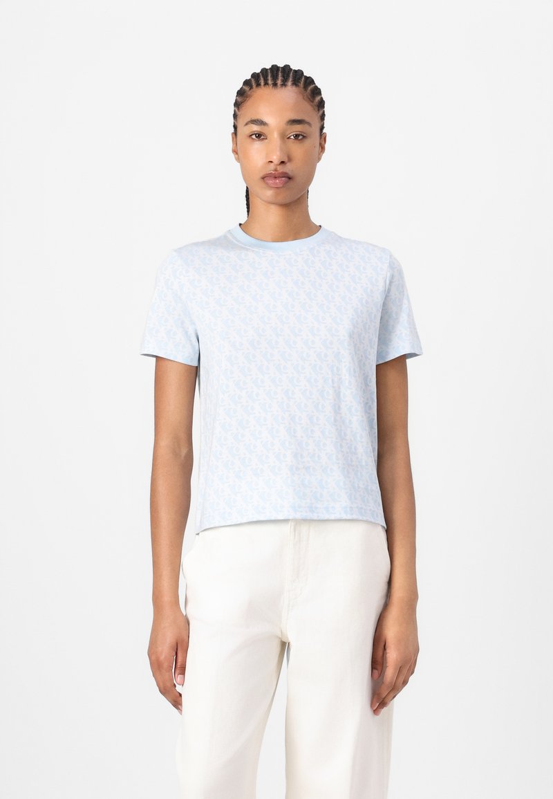 Camiseta de manga corta azul claro con un patrón blanco repetido, cuello redondo y un corte relajado, fabricada en suave algodón.