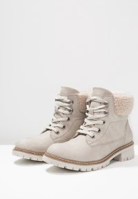 Beige suède enkellaarsjes met een zachte, met bont gevoerde kraag, ronde neus en veters, met een getextureerde rubbere sole en contrasterende stikdetails.