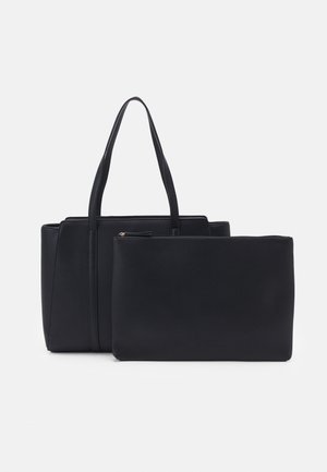 Sac cabas noir texturé avec de longues anses et une pochette assortie zippée, tous deux debout sur un fond blanc.