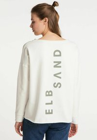 Sweatshirt à manches longues en coton blanc, avec une coupe décontractée, des épaules tombantes et le texte vert "ELB SAND" dans le dos.