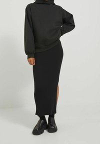 Svart hooded sweatshirt med ribbad mudd, tillsammans med en svart ribbad midikjol med en sidofick. Avslutad med svarta platåskor.