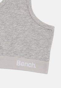 Hall hallide spordirinnaka pehme tekstuuriga, laiad rihmad ja heledat halli värvi elastne riba, millel on valged tähed "Bench."