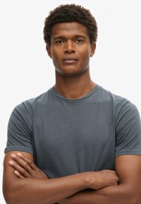 Grå kortærmet t-shirt lavet af glat bomuldsblandingsstof, med en rund halsudskæring og en subtil ribbet tekstur.