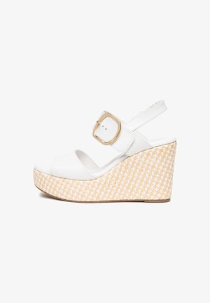 Sandale compensée en cuir blanc à bout ouvert, semelle plateforme tissée beige et grande boucle dorée sur la bride de cheville.