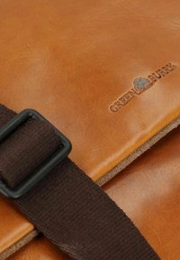 Borsa a tracolla in pelle marrone con una tracolla marrone scuro, caratterizzata da una finitura testurizzata e dettagli con logo in rilievo "GREEN FURRY."