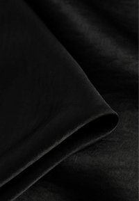 Mustvalge kangas sileda tekstuuriga, millel on kerge sära. Rullitud serv, mis näitab puhast viimistlust, koos peene, kootud mustriga.