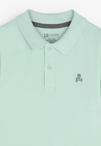 Polo di un verde menta chiaro realizzato in 100% cotone, con un motivo testurizzato, un colletto classico e un piccolo logo a forma di teschio sul lato sinistro del petto.