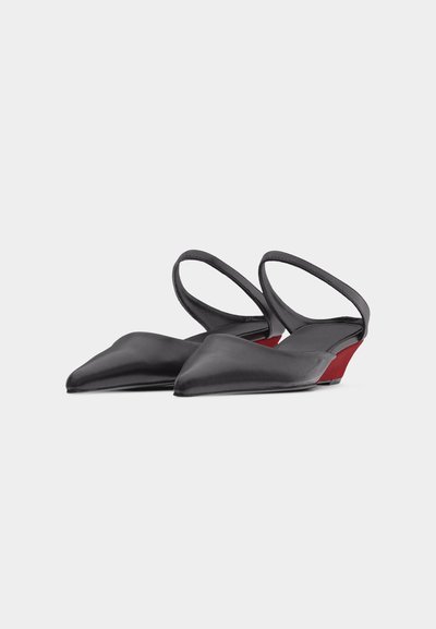 Μαύρα γυναικεία παπούτσια με μύτη σε σχήμα αιχμής και λουράκι πίσω, με χαμηλές κόκκινες πλατφόρμες σε λευκό φόντο.