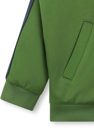 Giacca verde intrecciata con polsini a coste, caratterizzata da un accento blu navy lungo la manica e una tasca nascosta sul lato.